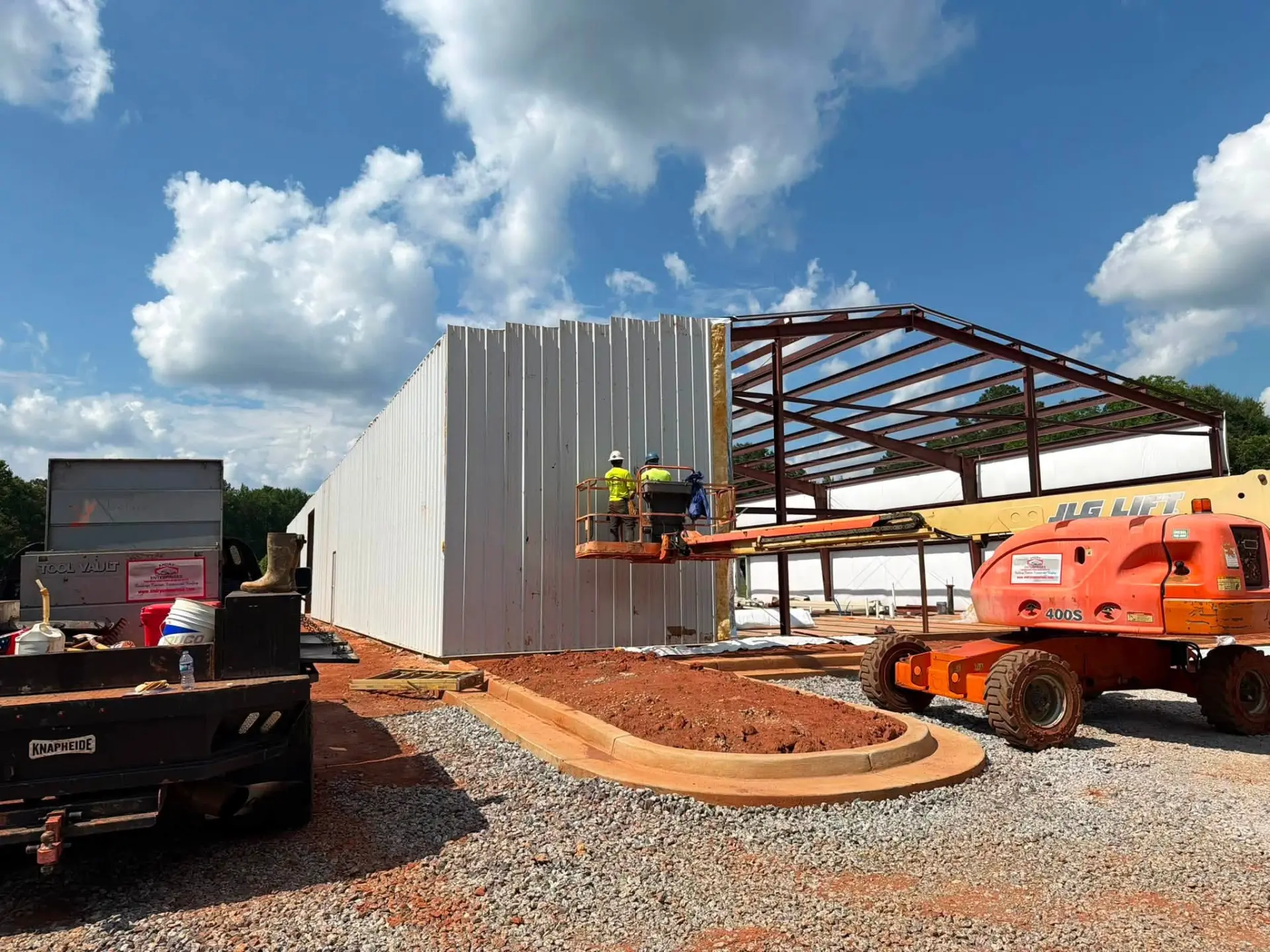 Crew installing metal wall panels on a commercial PEMB frame